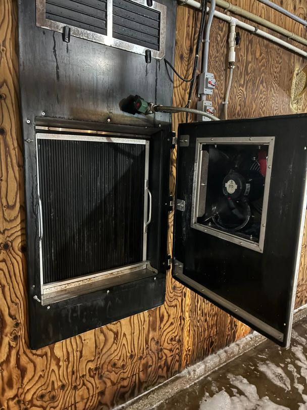 Cleaned hot-water heater in a poultry barn, coil and fan motor washed back to bare black metal